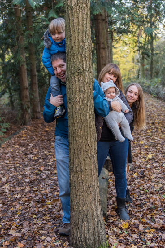 Family playing peek-a-boo behind tree